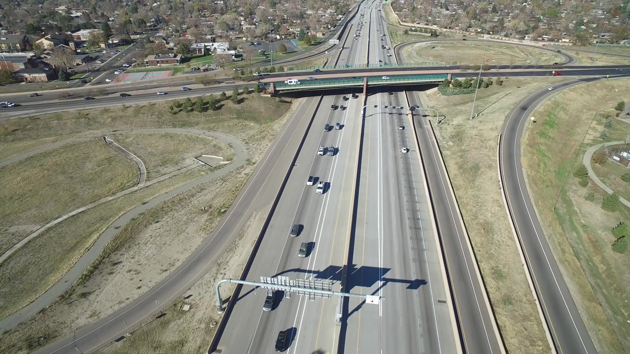Aerial frame of Hidden Lake, Colorado traffic moving along divided highway lanes beneath a green overpass, with ramps and no visible people.