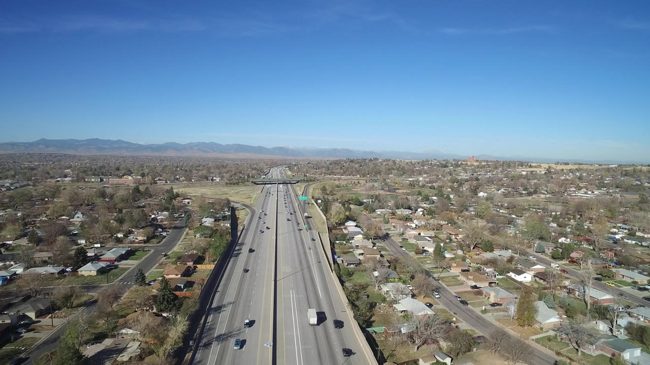 Aerial view of a freeway through a residential area under blue sky.