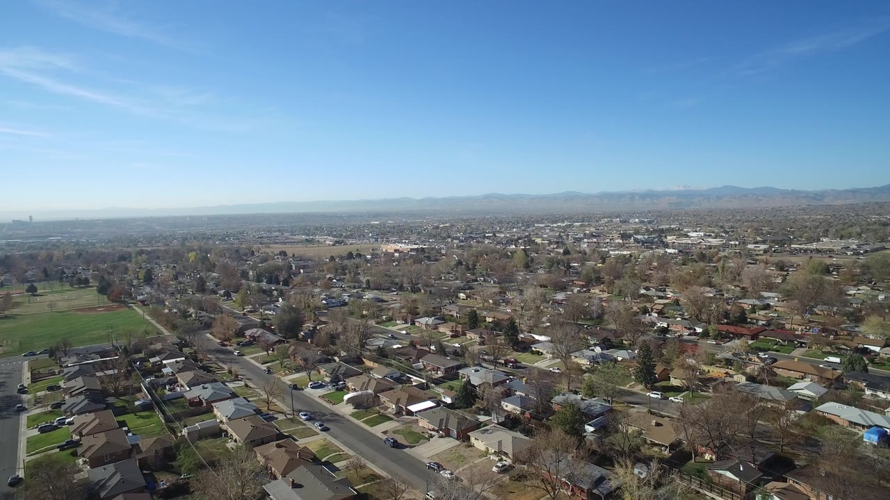 Aerial view of suburban homes and streets under a blue sky.