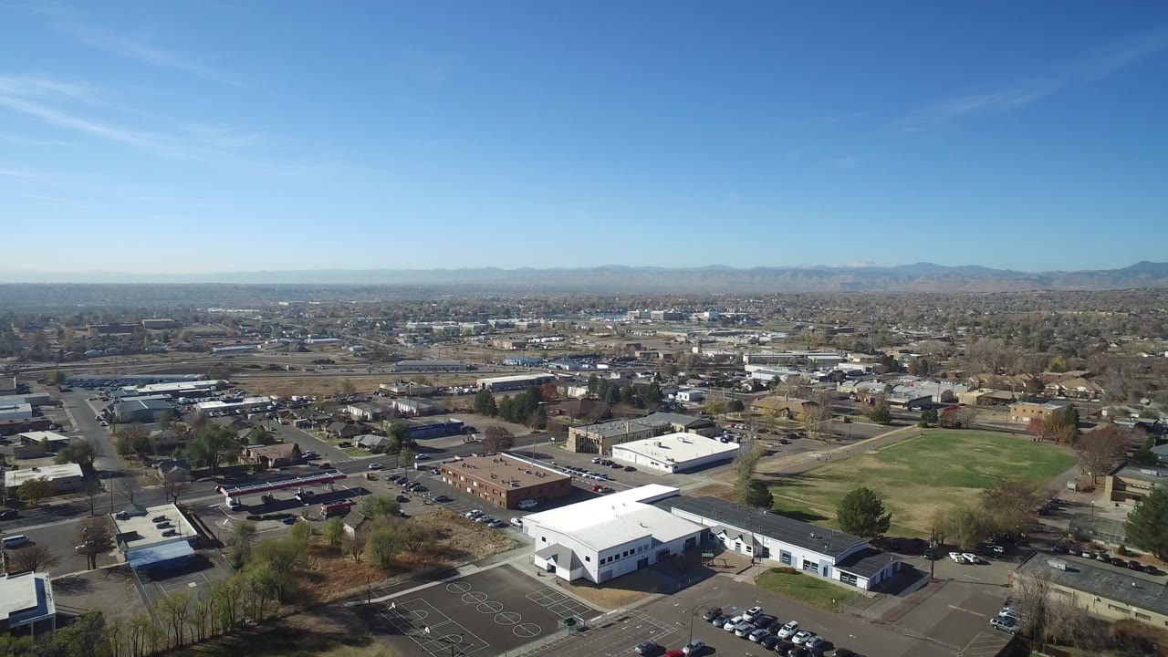 Aerial neighborhood view with white roofs in the foreground and mountains along the horizon.