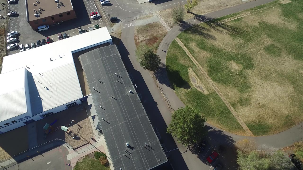 Overhead view of a white-roofed building beside grass and paths