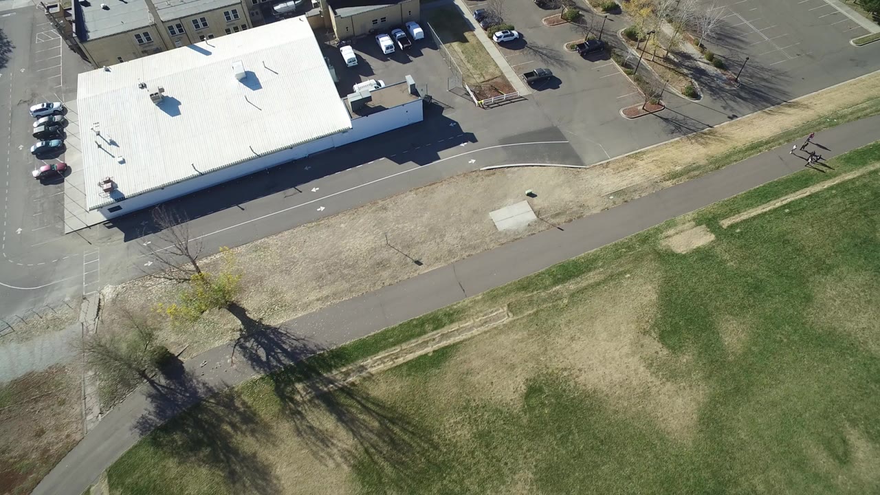 Aerial view of a white-roofed commercial building beside grass and parking