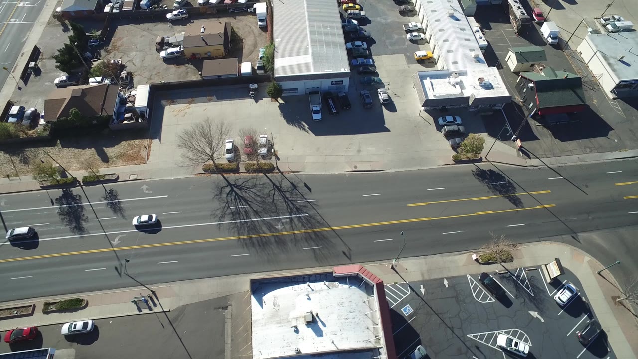 Drone-like overhead view of a commercial block along a wide street.