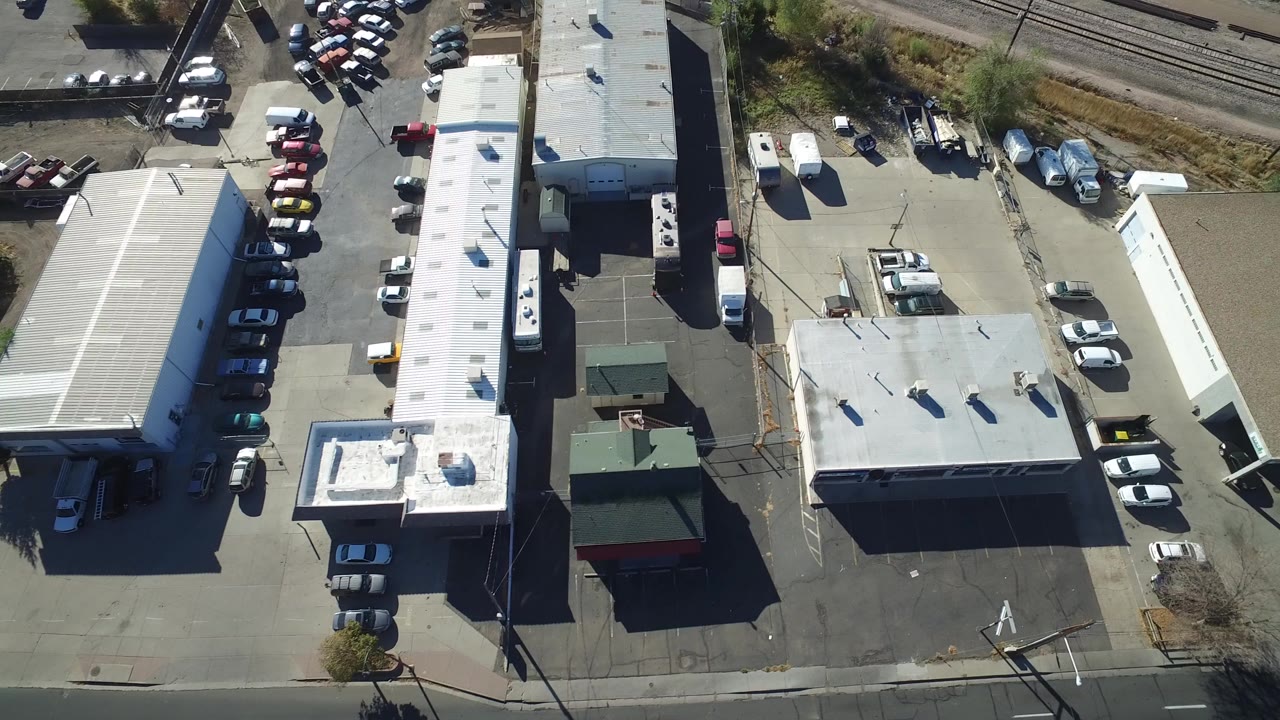 Overhead view of commercial buildings and parking lots beside railroad tracks.