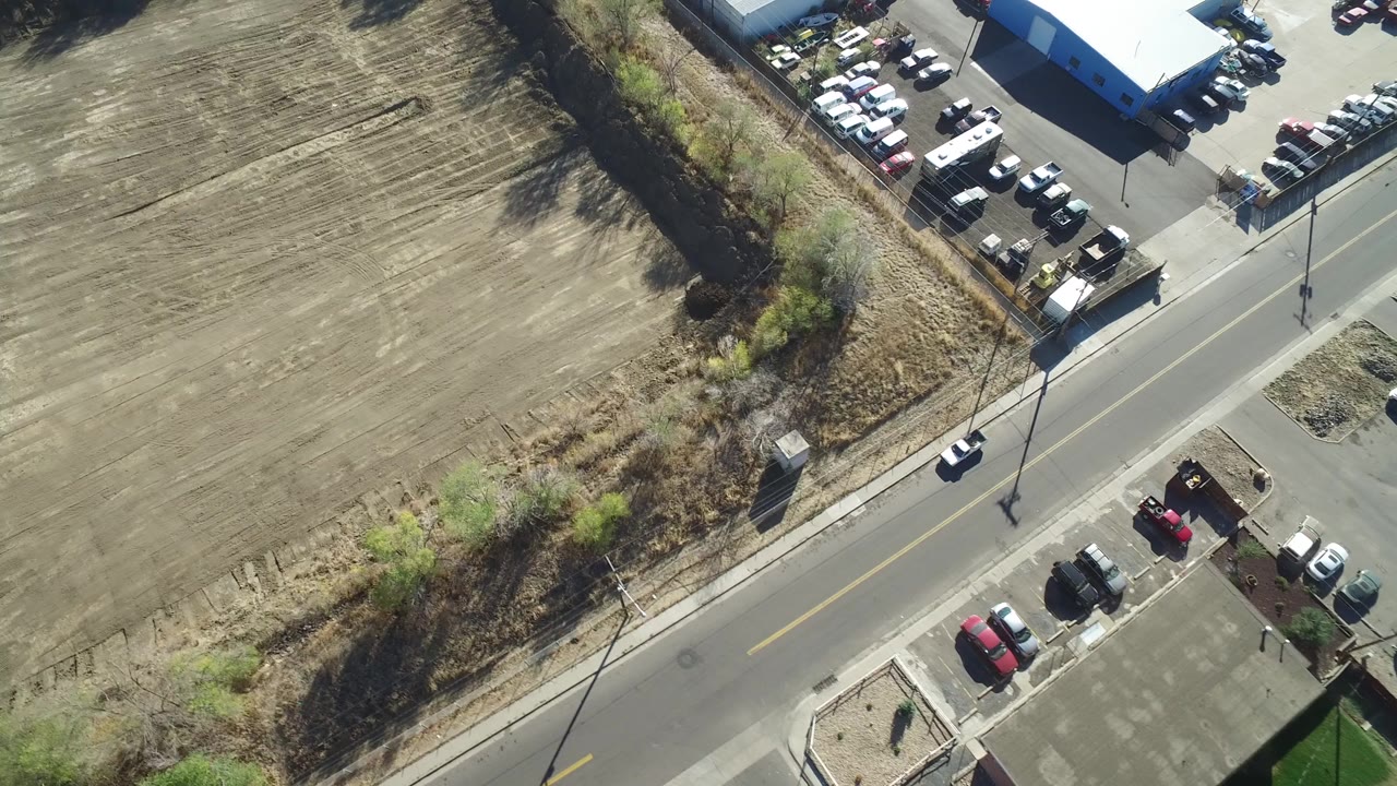 Aerial view of a road beside a plowed field and parking lots.