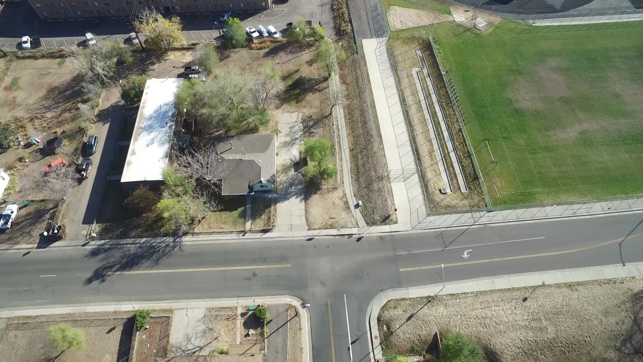 Opening overhead frame in Hidden Lake, Colorado, showing a road, sidewalks, a single-family house, a large green lawn, parked vehicles, trees, and no visible people.