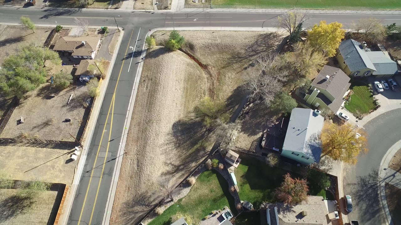 Overhead view of suburban houses beside a two-lane road and dry lots.