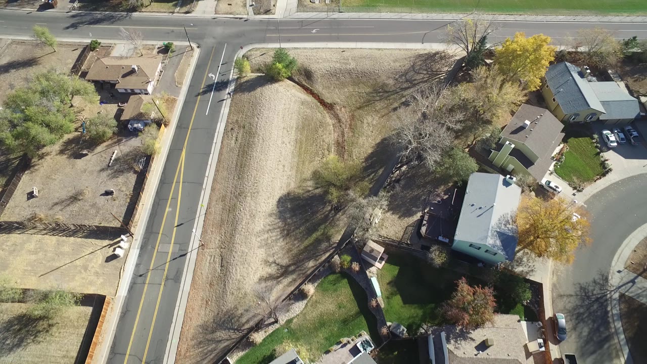 Overhead frame in Hidden Lake, Colorado showing rooftops, a curved neighborhood road, driveways, fences, bare trees, yellow foliage, and no visible people.