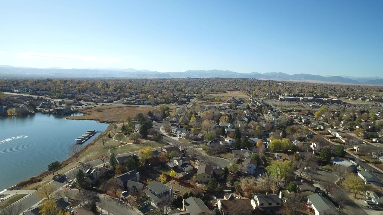Aerial view of residential blocks beside a lake under a clear sky.