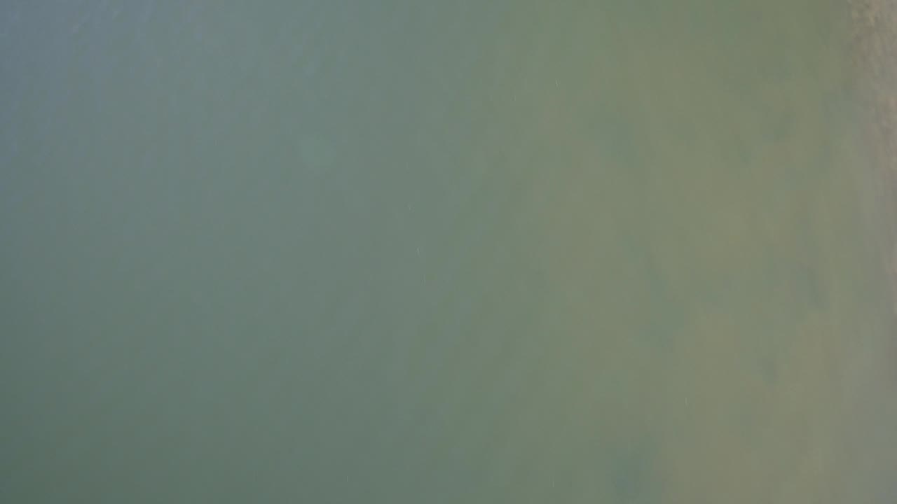 Aerial frame over Hidden Lake, Colorado, showing only grey-green water with faint darker bands and no visible people.