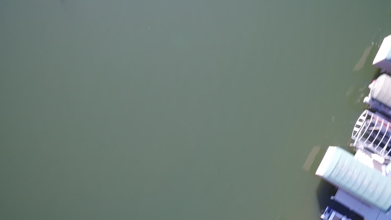 Overhead green lake water with part of a dock or boat at the right edge.