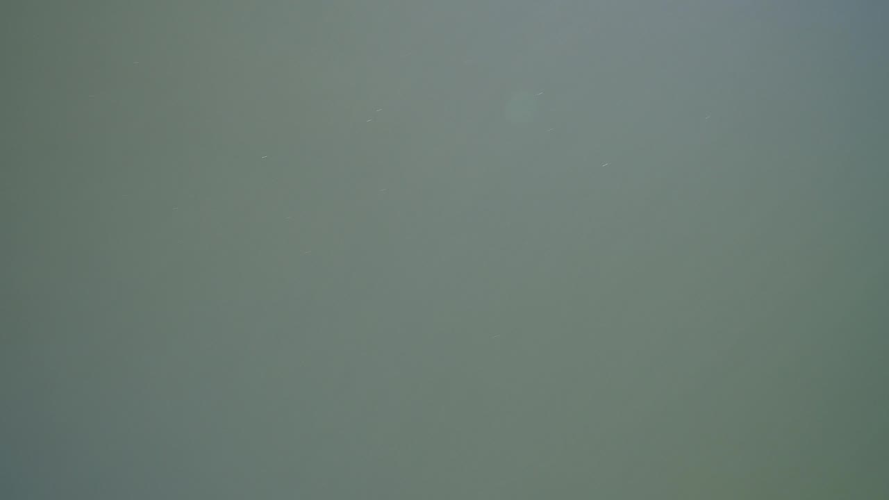 Green-blue lake surface at Hidden Lake, Colorado, nearly filling the frame with faint specks on the water and no visible people.