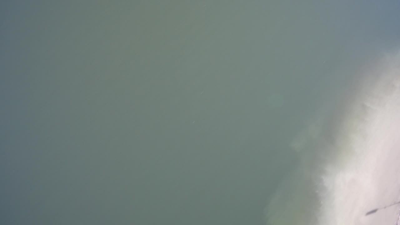 Blue-green surface with a bright white form along the lower right edge.