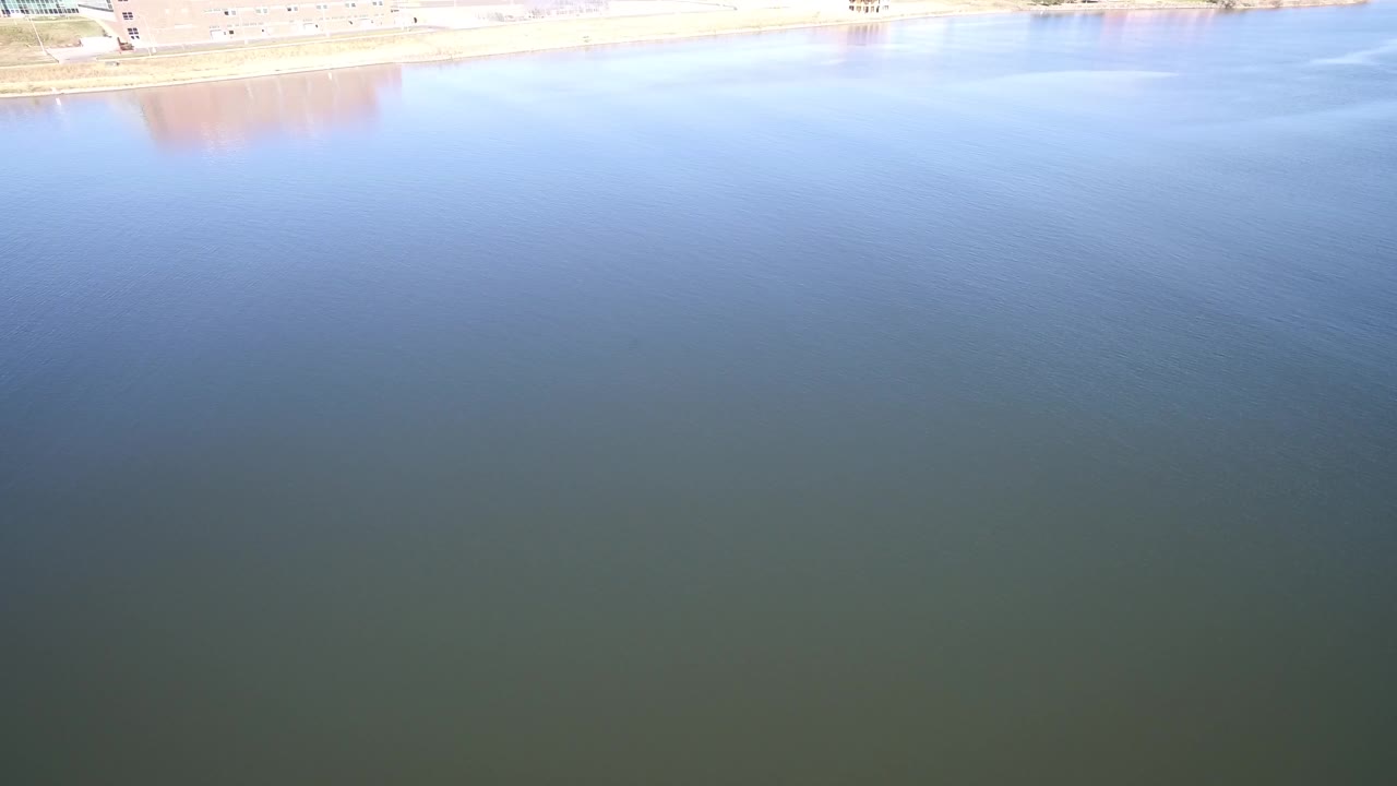Blue-green lake water with bright shoreline reflection at the top edge.