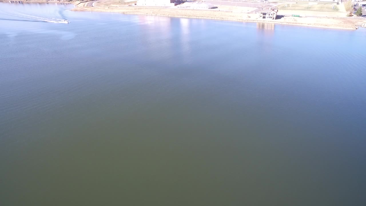 Aerial view of blue-green lake water with a bright shoreline at the top edge.