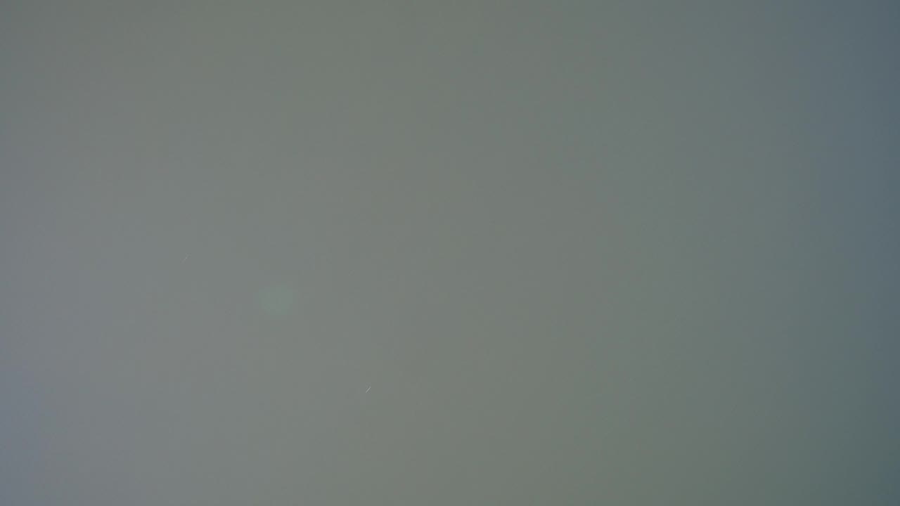 Second frame from the Hidden Lake, Colorado clip showing the same flat gray-silver field, with a small pale speck on the left and no visible people.