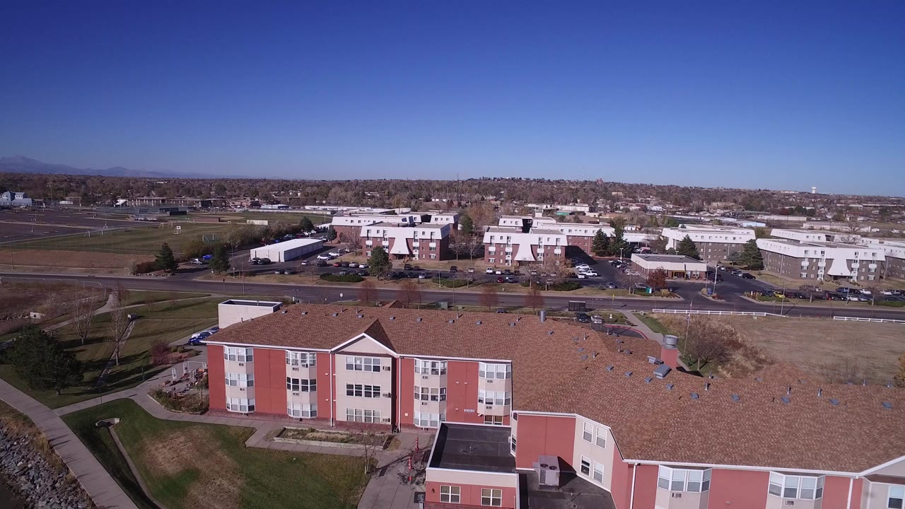 Aerial view of a red and cream building complex with lawns, roads, and distant mountains.