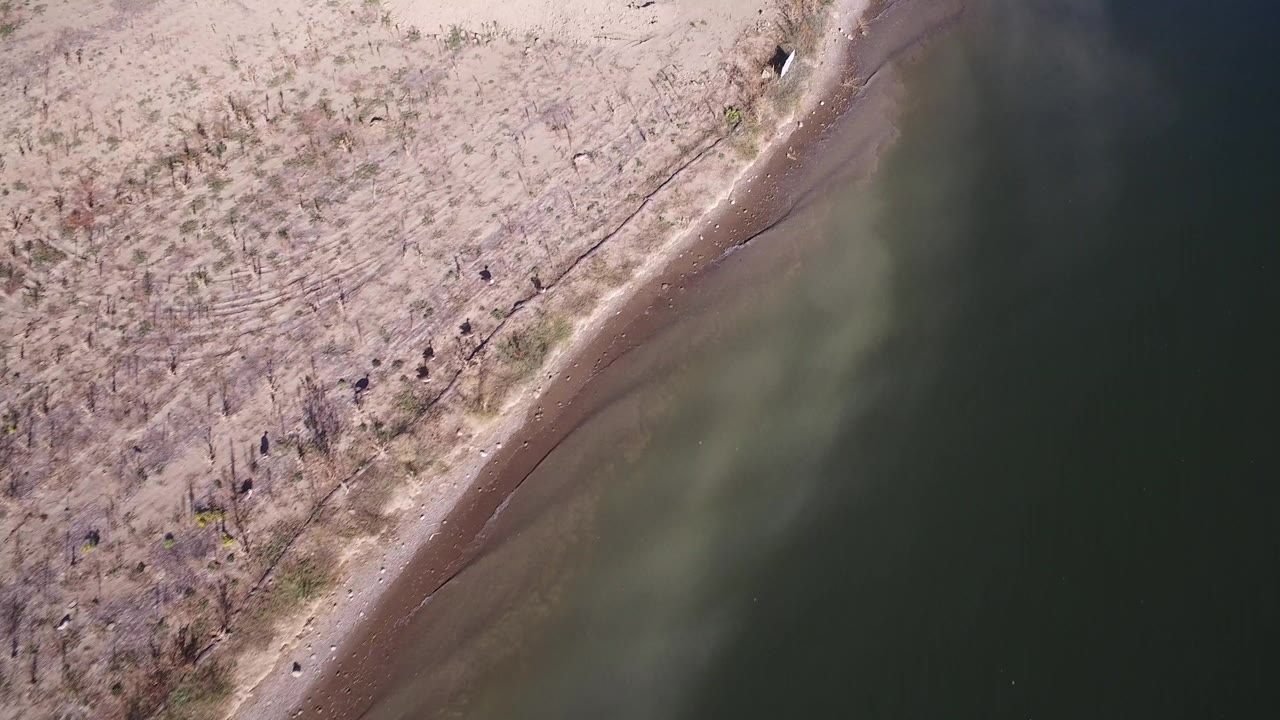 High overhead view of a diagonal lake shoreline and dry land.