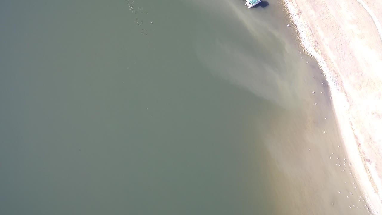 Aerial lake shoreline with a small dock structure near the top edge.