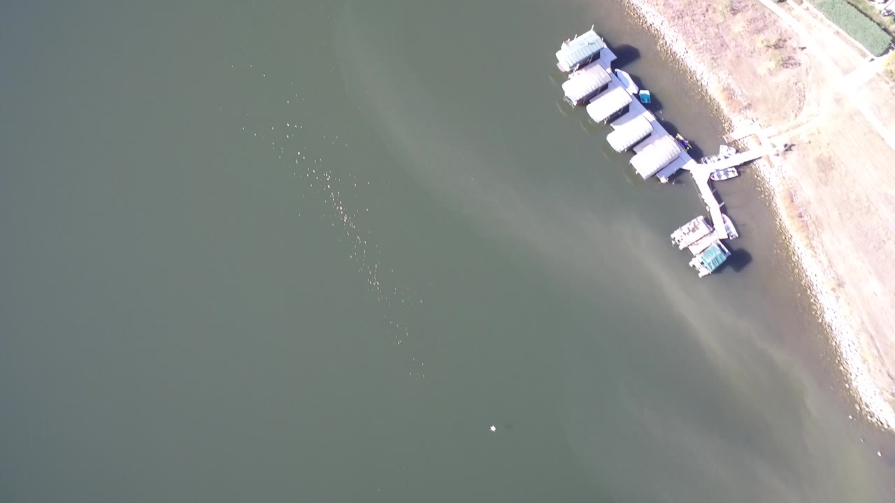 Overhead lake water beside a small dock and sandy shoreline.