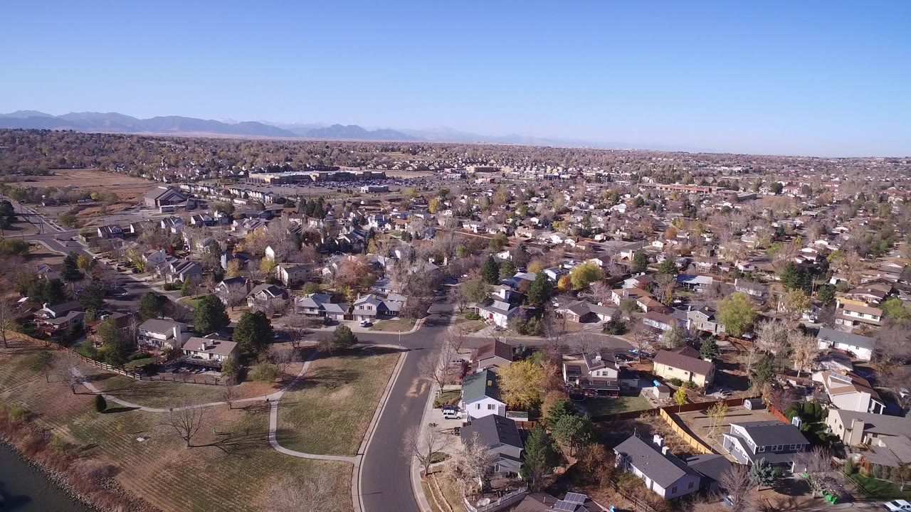 Aerial view of suburban homes, roads, trees, and distant mountains.