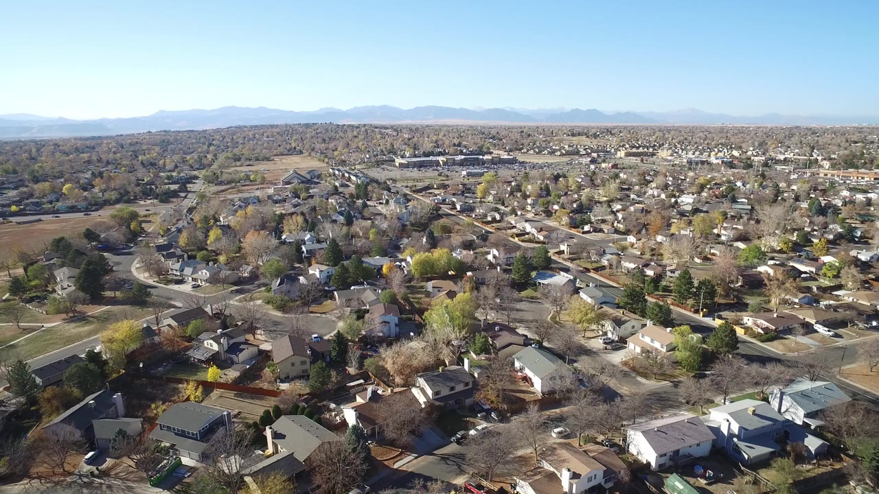 Aerial view of suburban homes and roads below a mountain horizon.