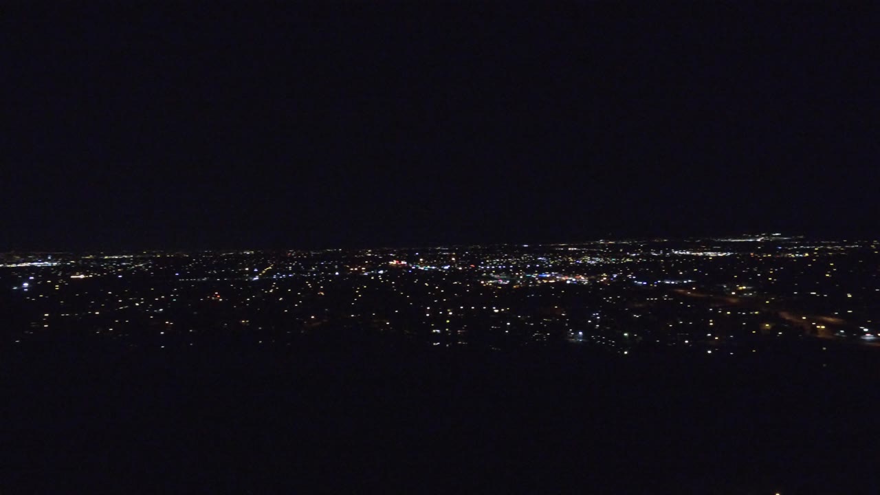 Denver city lights stretch across the upper horizon while the lower frame remains mostly black, with no visible people.