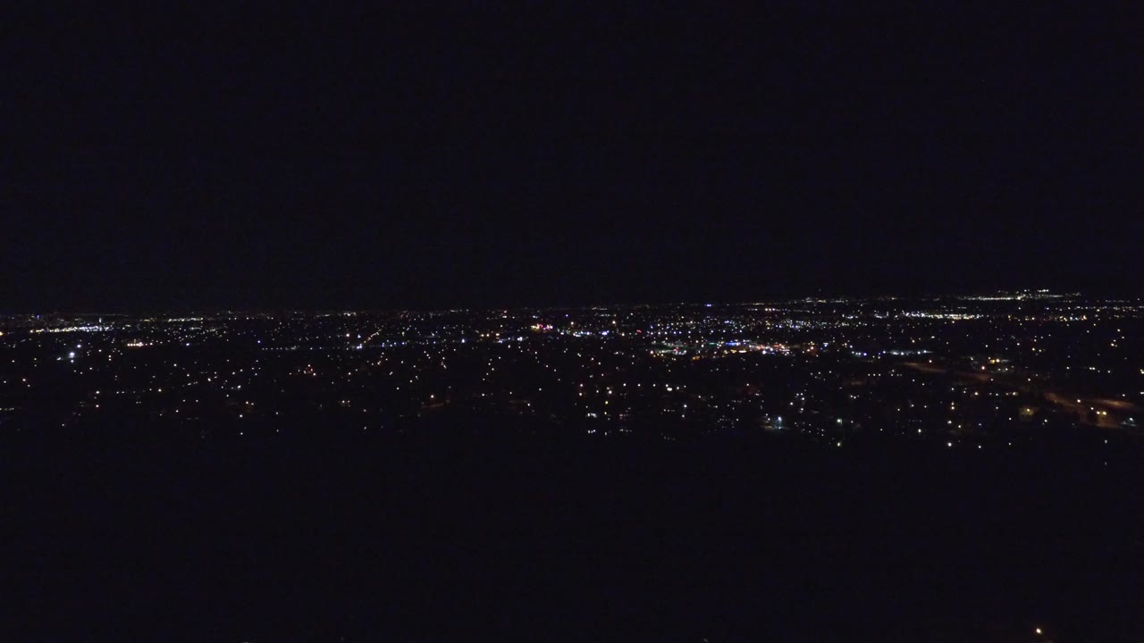 Wide dark night sky above distant city lights.