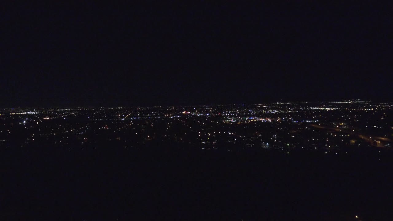 Denver city lights continue across the low horizon with small bright clusters and a dark open sky filling most of the frame, no visible people.