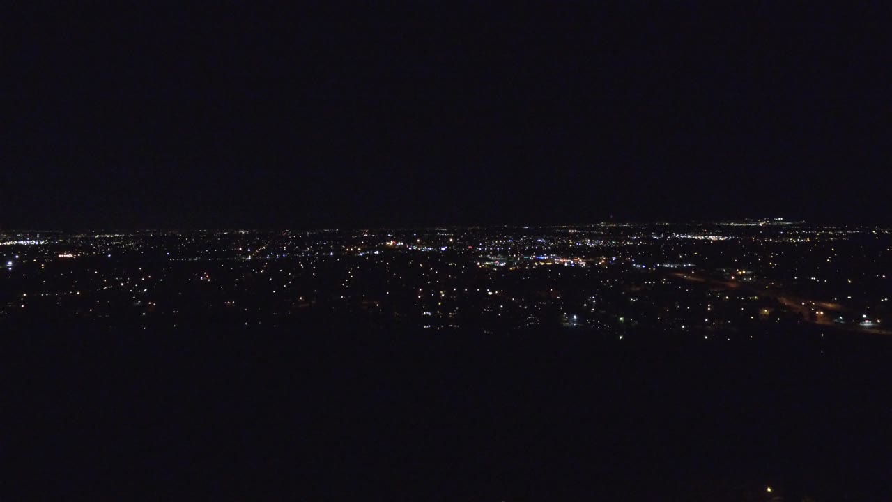 Denver city lights stretch across the horizon while the lower half of the frame remains nearly black, with no visible people.