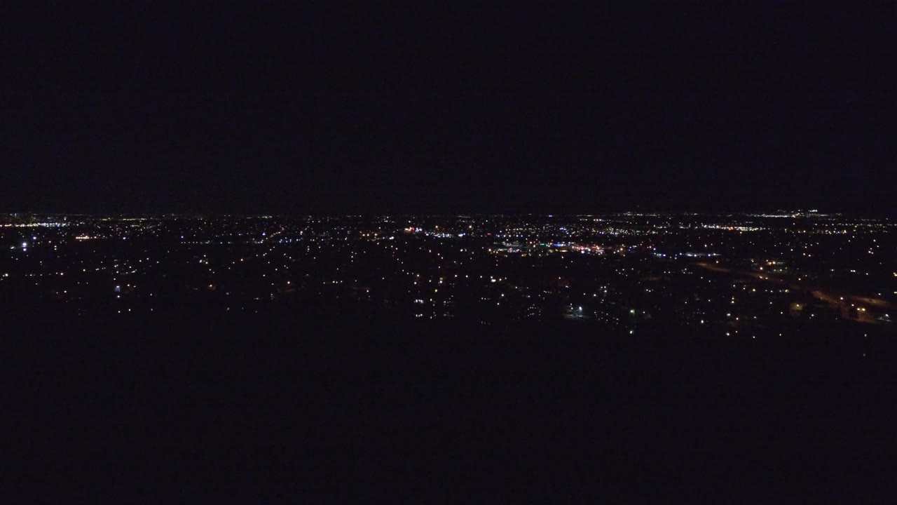 Dark city lights spread along a nighttime horizon.