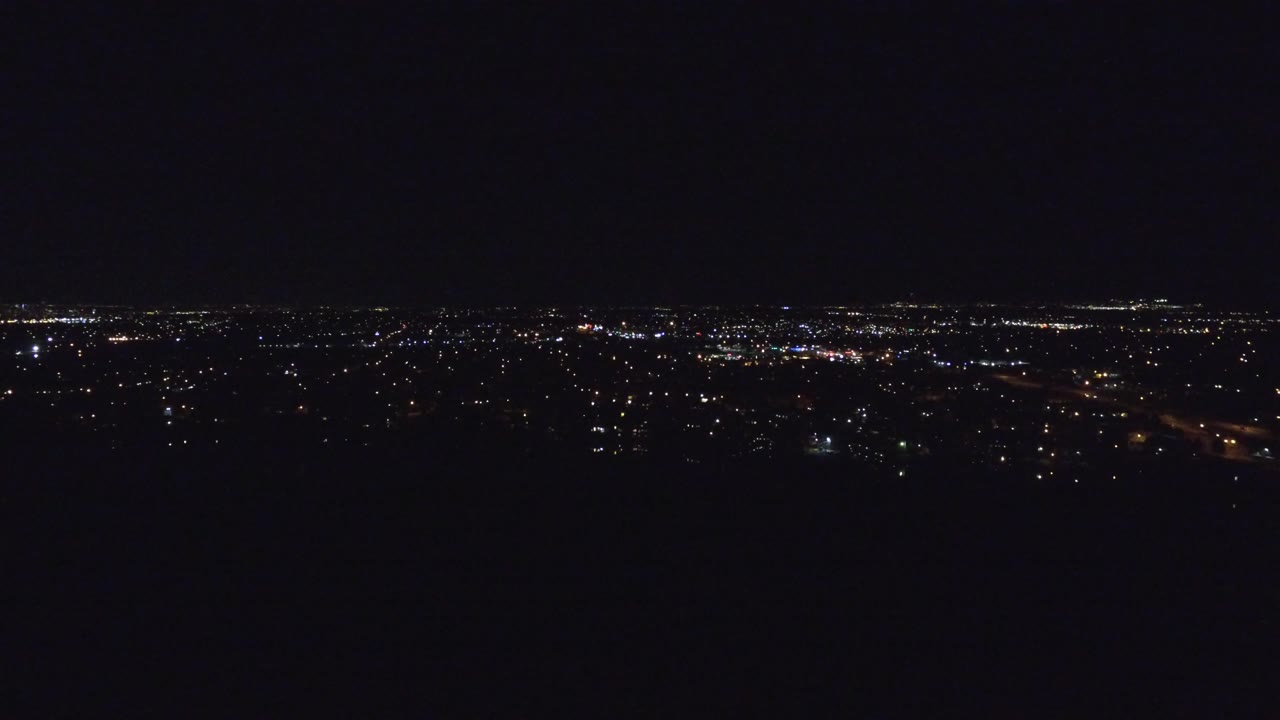 Second frame showing Denver's distant night lights stretching across the horizon beneath a mostly black sky, with no visible people.