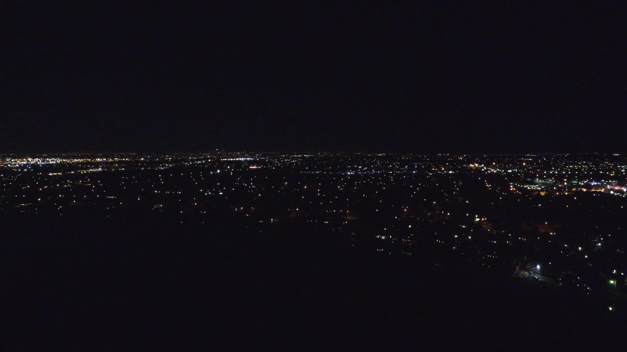 Sparse night lights and bright clusters across a distant city.