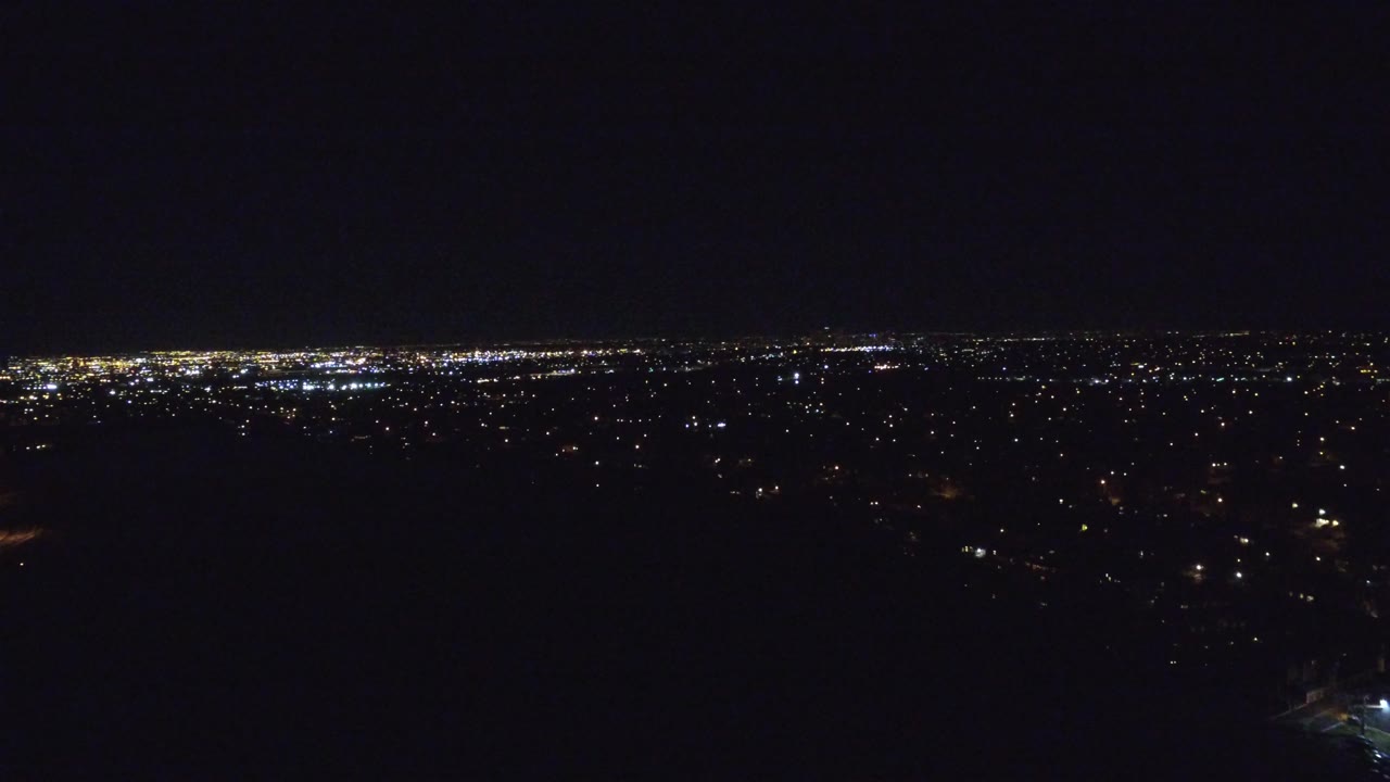 Wide night view of city lights under a dark sky.