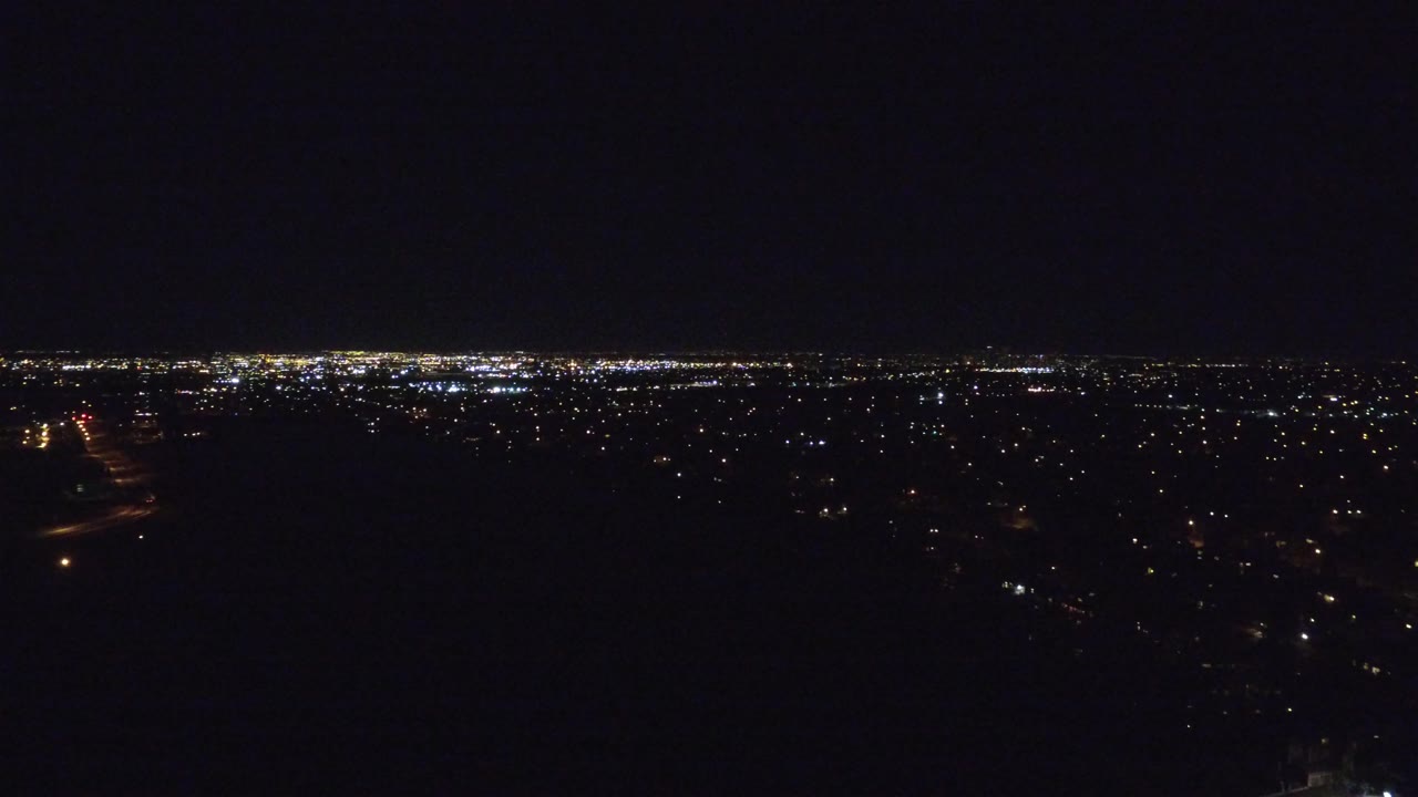 Wide nighttime view over Denver with scattered city lights below a large black sky and no visible people.