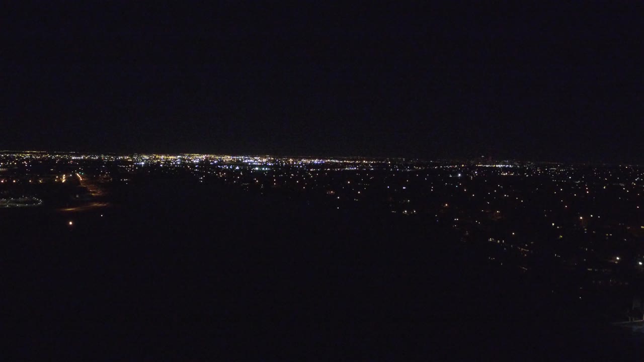 Dark night view of distant city lights under a black sky.
