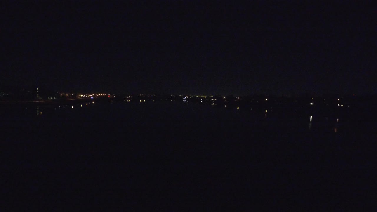 Dark night horizon with distant city lights.