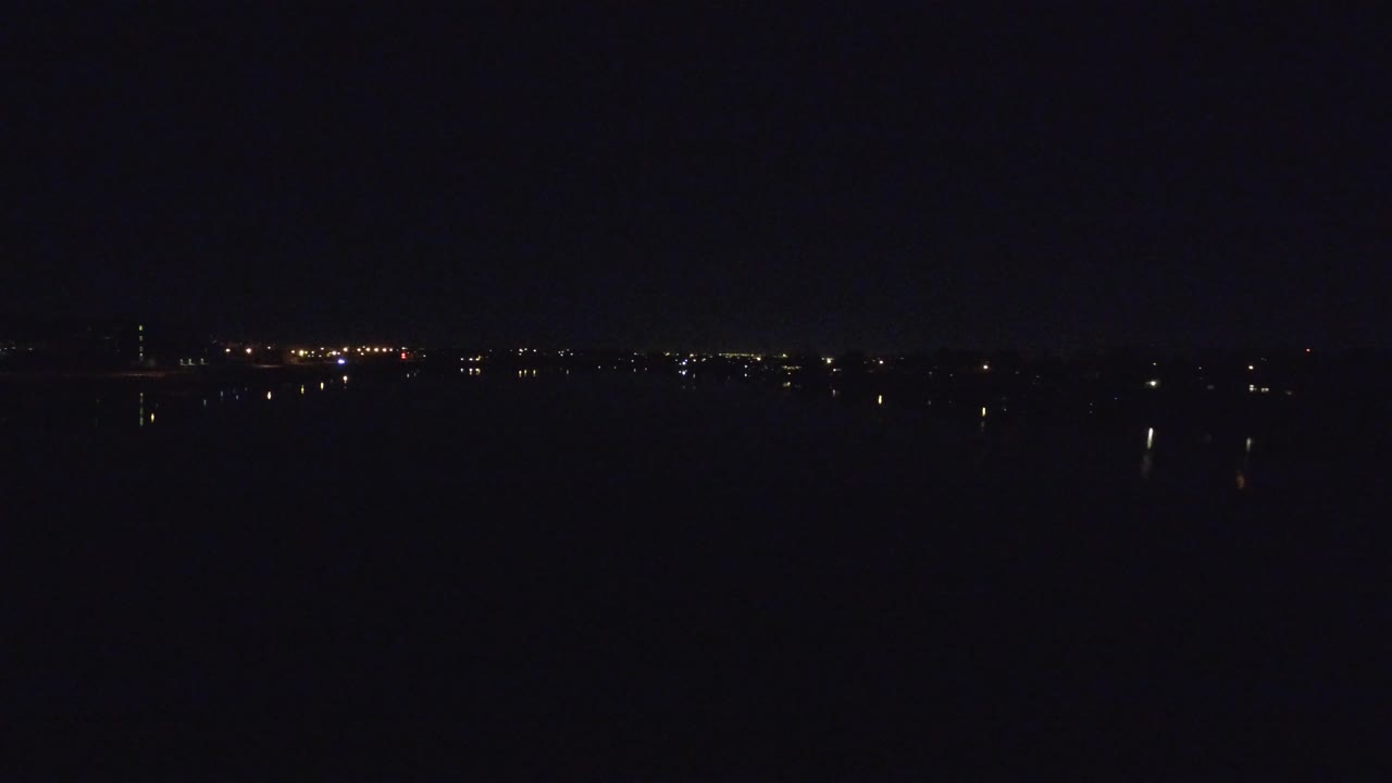 A second Denver night frame holds on the distant illuminated city line beneath a nearly black sky, with no visible people.