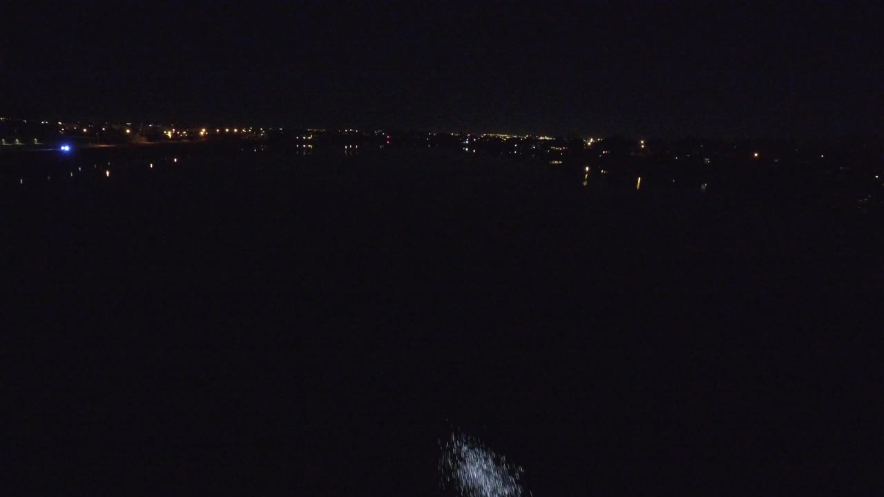 A dark Denver night runway scene with a thin line of distant lights across the horizon, a small blue light at left, and no visible people.