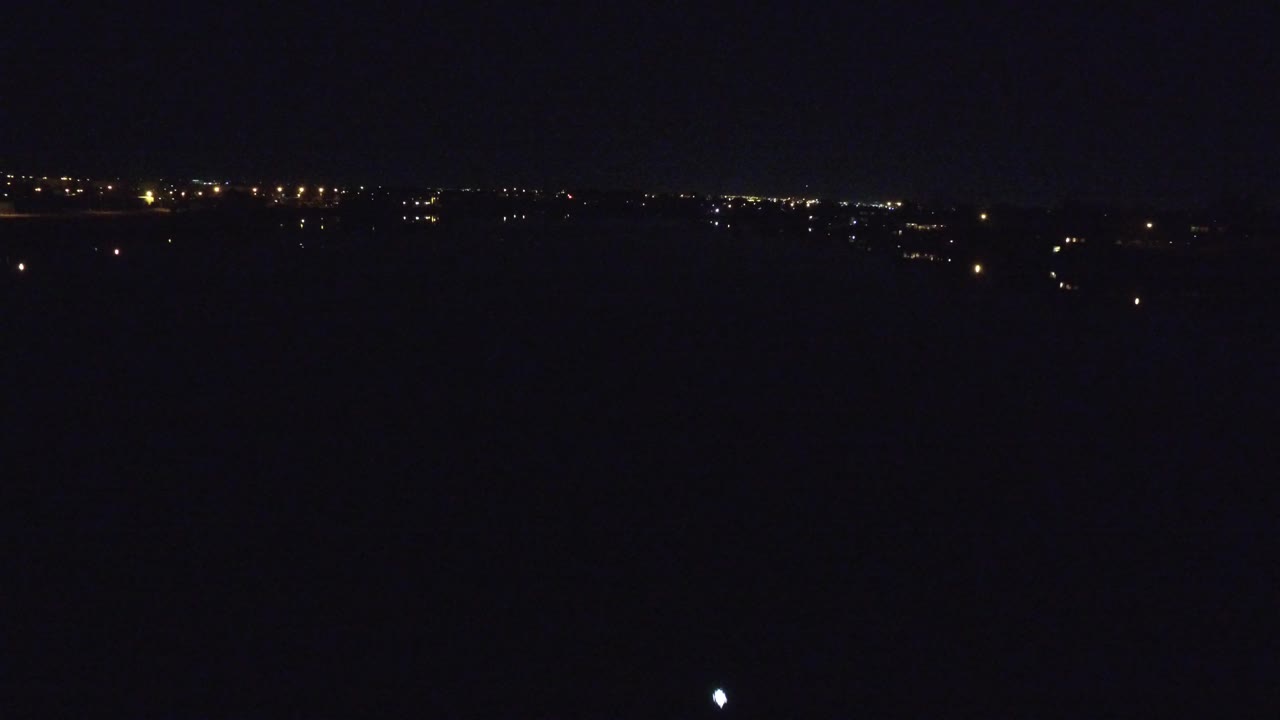 Denver, Colorado night view with a mostly black foreground, scattered warm lights on the distant horizon, and no visible people.