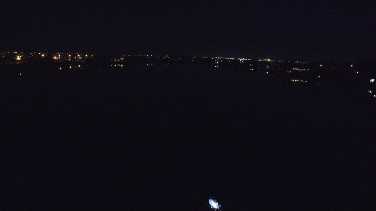Wide Denver, Colorado night view over dark water with distant horizon lights and a small bright light on the water, no visible people.