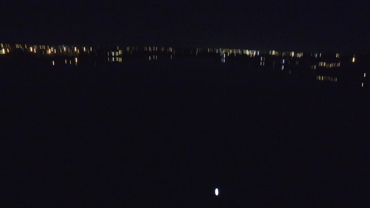 Dark lake at night with distant shoreline lights.