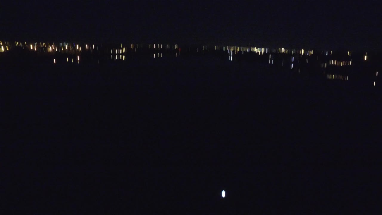 Denver, Colorado lake at night with a thin cluster of far shore lights across the top of the frame and mostly black water below, with no visible people.