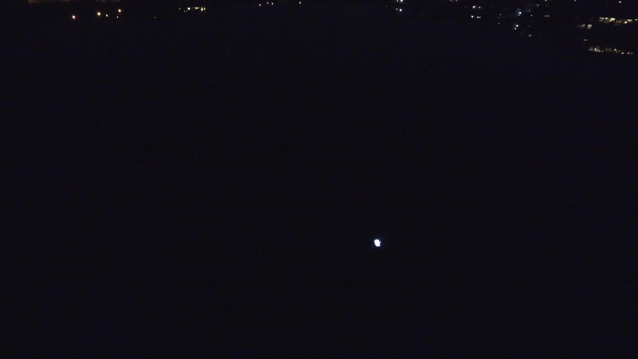Small white reflection on dark lake with scattered distant lights