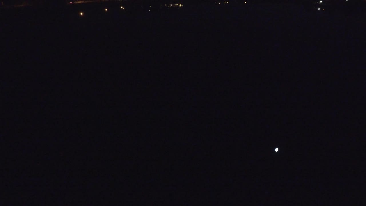 A Denver night frame shows one small bright white point above faint warm lights along the horizon, with no visible people.