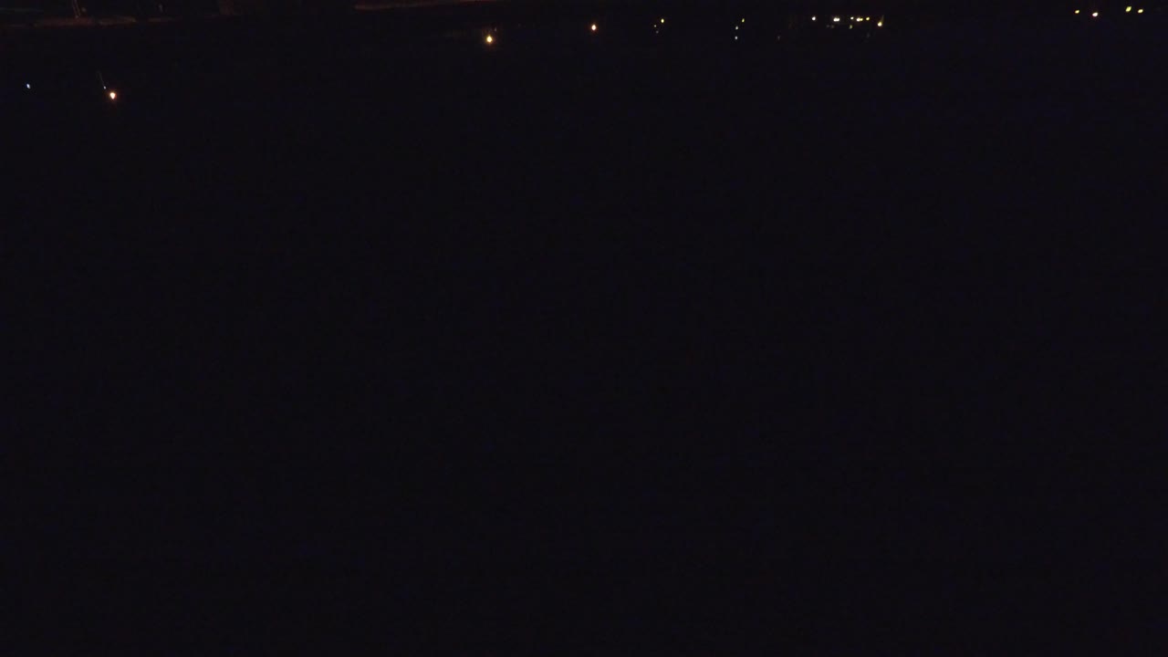 A sparse line of orange and white lights marks a dark Denver night street scene with no visible people.