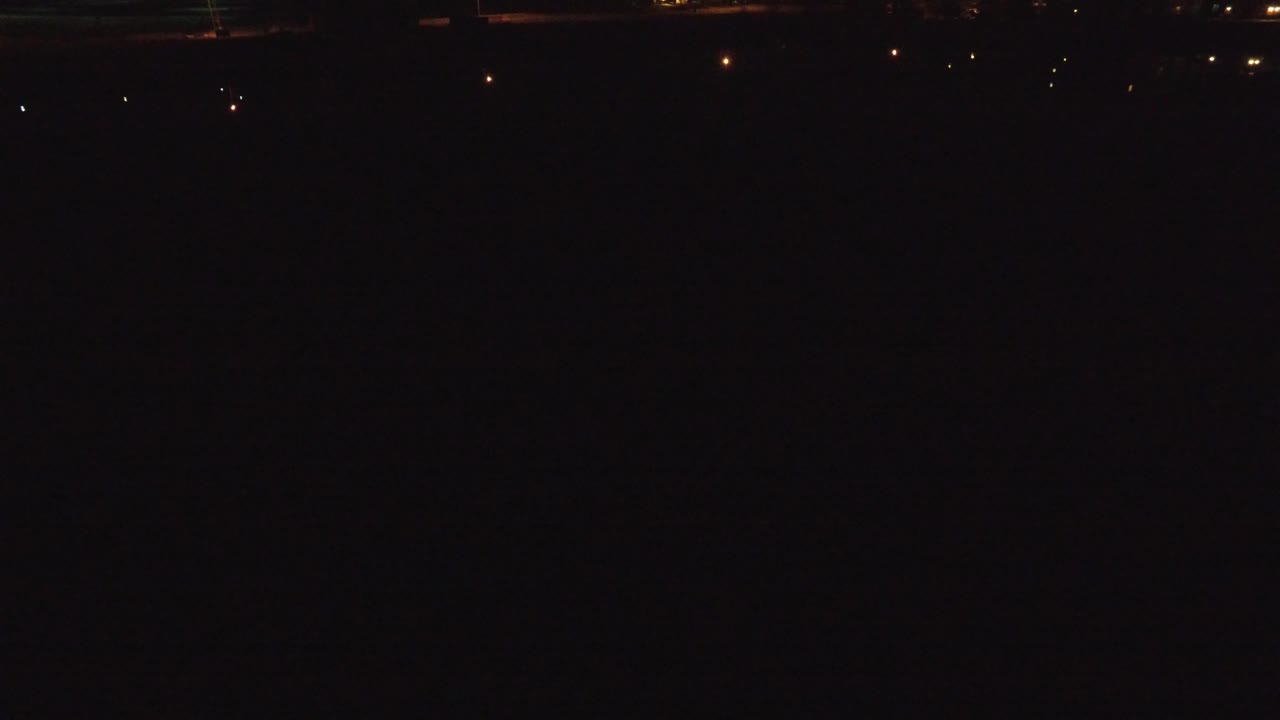 Mostly black frame with a few dim lights and faint horizontal structure.