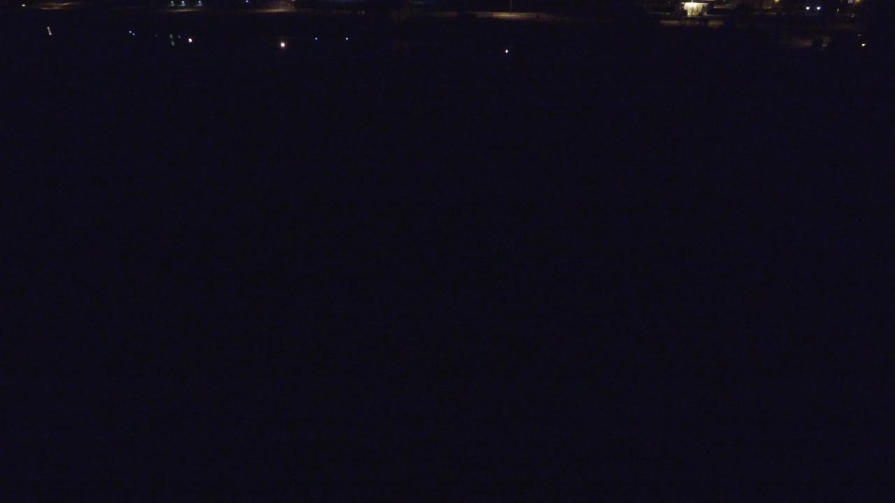 Very dark Denver night frame with a faint horizontal bridge or roadway near the top and scattered small lights, with no visible people.