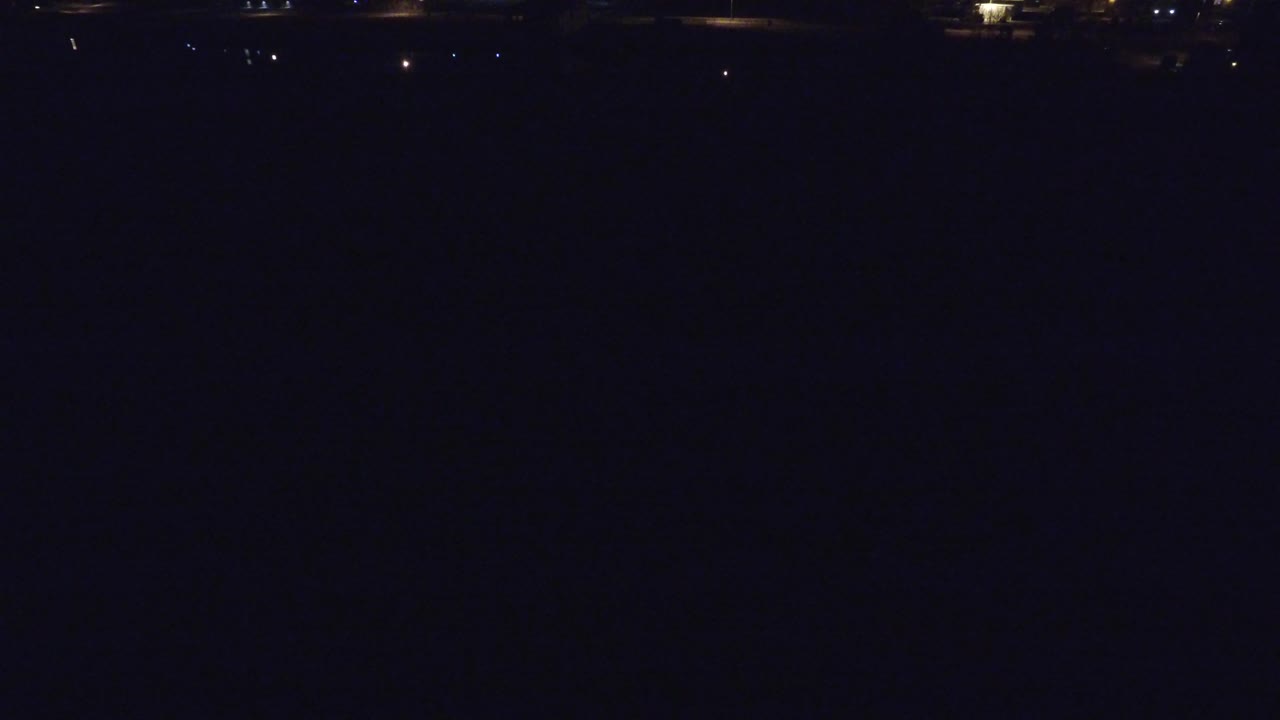 Denver night view with tiny white lights and a dim amber glow tracing a distant bridge or road across the upper frame, with no visible people.