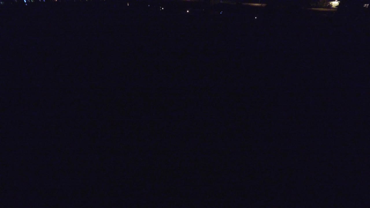 Mostly black aerial night view with a few tiny distant lights